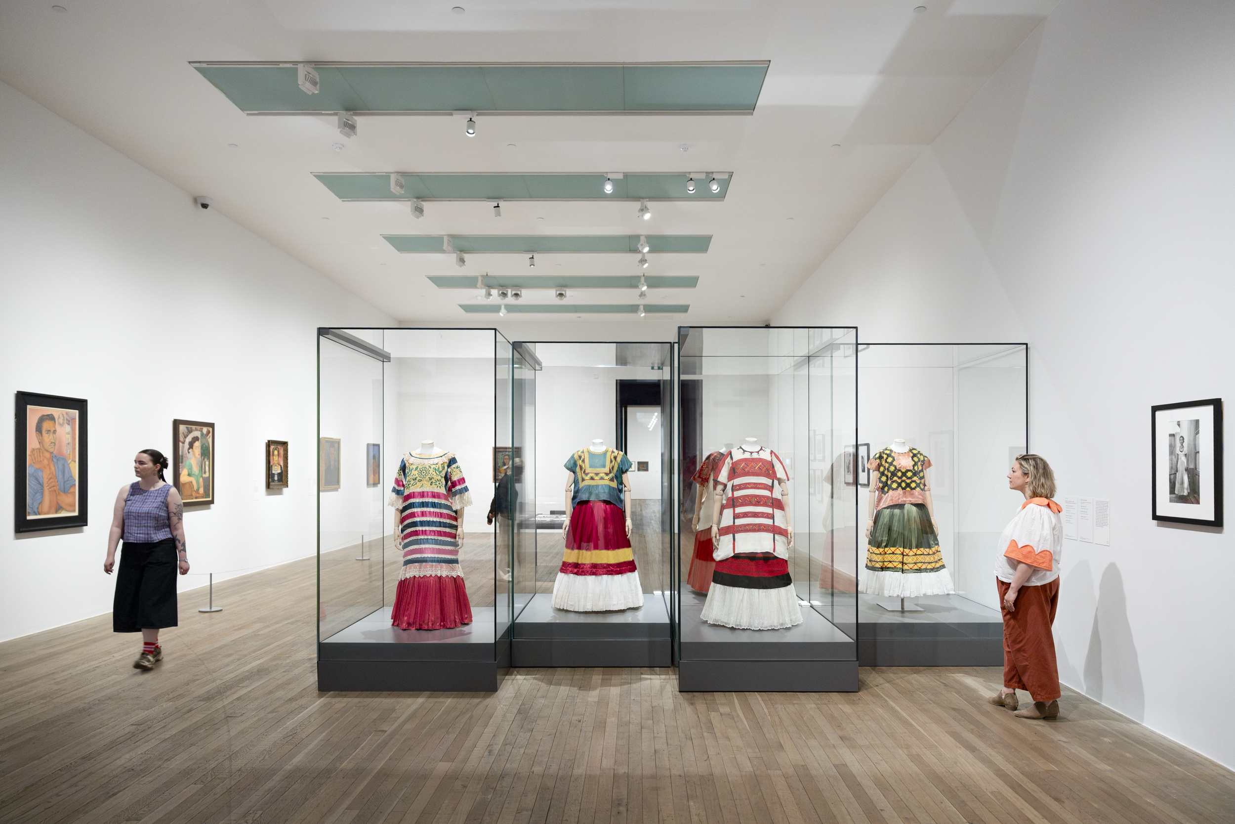 Visitors view Frida Kahlo's traditional Mexican Tehuana dresses in glass cases at the Tate exhibition.